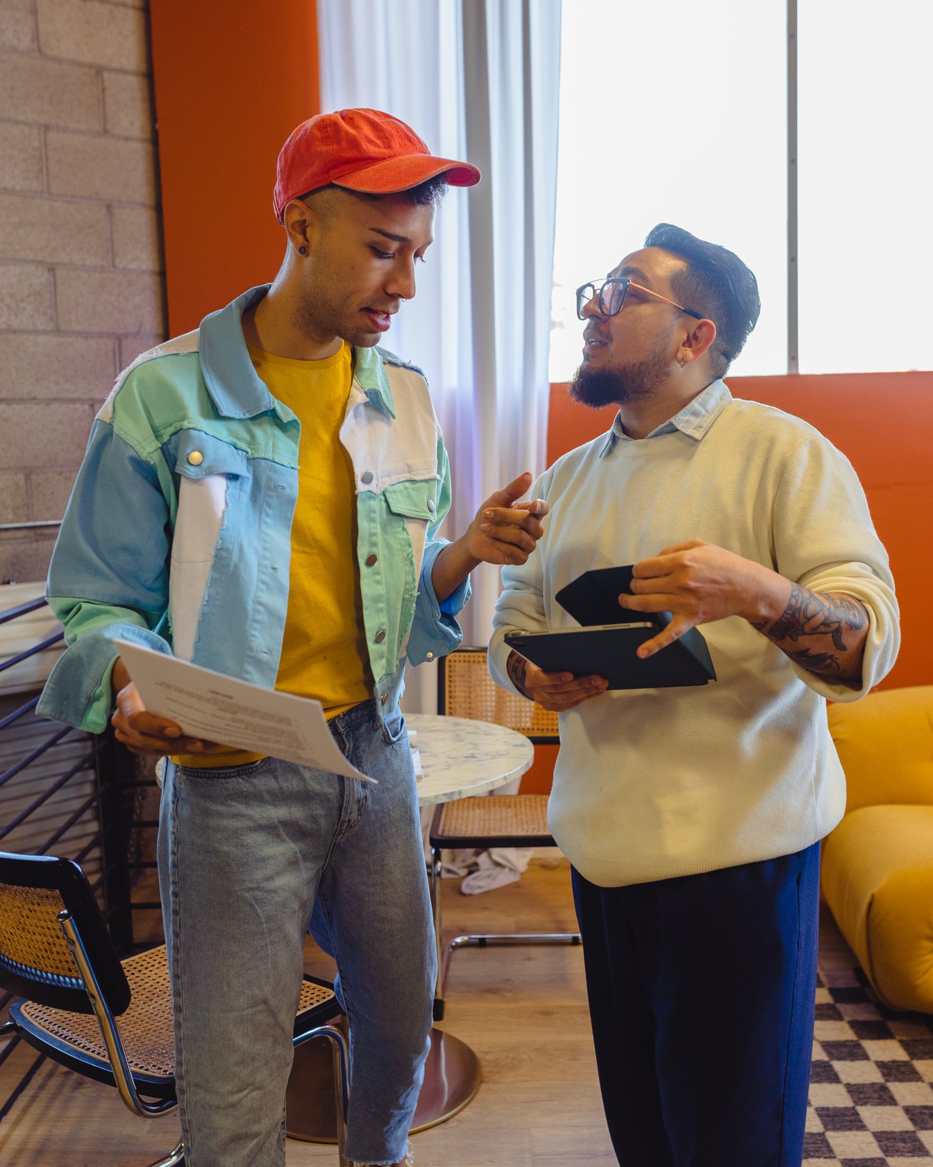 a photo of two people standing in front of each other, one is holding documents, the other is holding a tablet